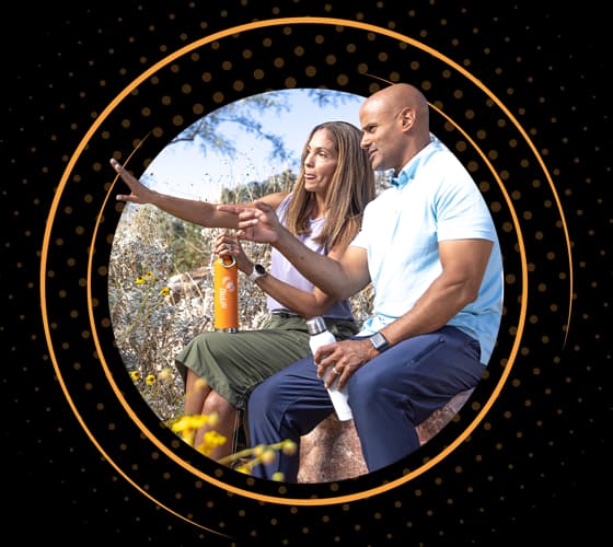 A young couple resting outdoors while on a hike.